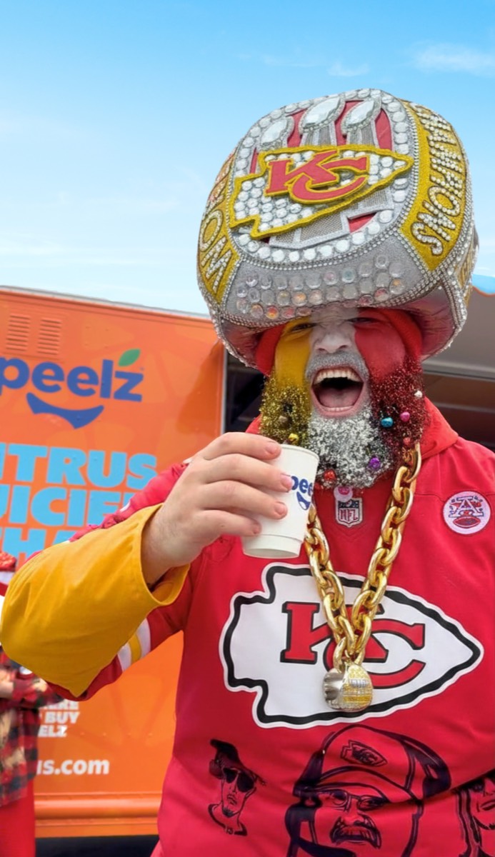 A Kansas City fan in a giant ring hat drinking at the Peelz truck